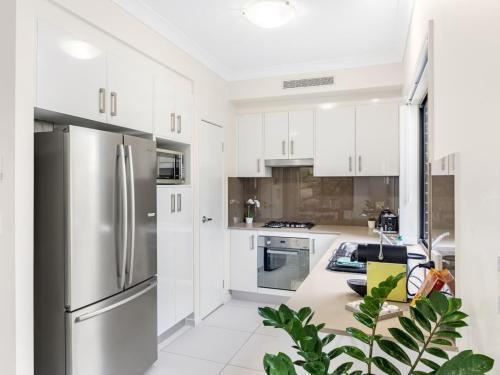 a kitchen with white cabinets and a stainless steel refrigerator at 3BD Townhouse close to shops, transport with carpark in Brisbane