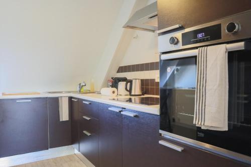 une cuisine avec des armoires brunes et un appareil noir dans l'établissement {L'Essentiel}, calme, proche autoroute, à Mulhouse