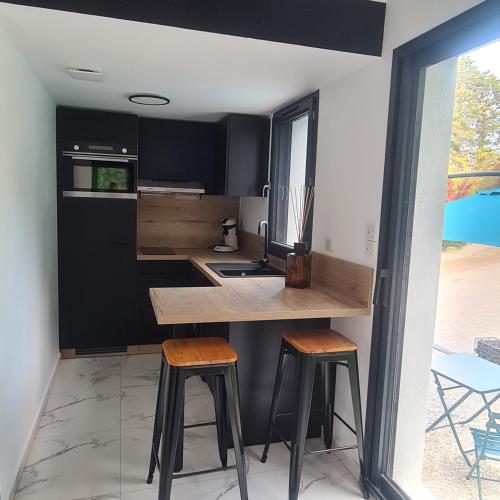 - une cuisine avec un comptoir et deux tabourets dans l'établissement les palmiers de l'isle, à Lagnes