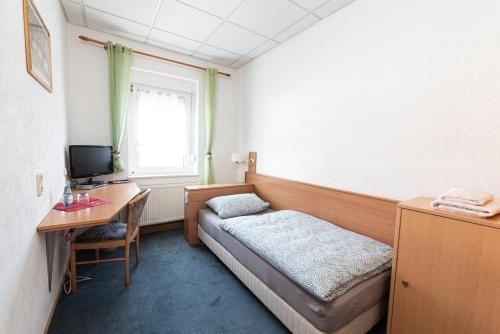 a room with a bed and a desk with a computer at Pension Greiser in Leipzig