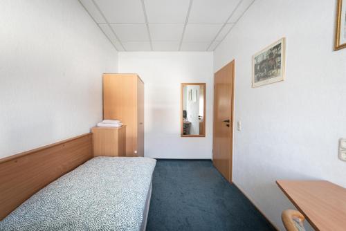 a small room with a bed and a desk at Pension Greiser in Leipzig