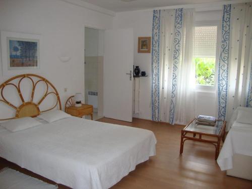 a bedroom with a white bed and a couch at Appartement cosy à Saint-Raphaël - 65 m² - Jardin privé in Saint-Raphaël