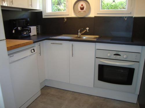 une cuisine avec des armoires blanches et un évier dans l'établissement Appartement cosy à Saint-Raphaël - 65 m² - Jardin privé, à Saint-Raphaël