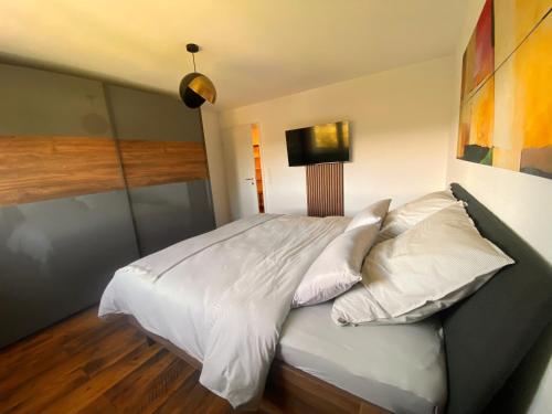 a bedroom with a bed with white sheets and pillows at Charming Loft Ferienwohnung Bodensee in Meckenbeuren
