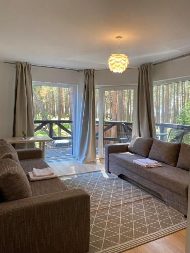 a living room with two couches and a large window at Kopų draugai in Palanga