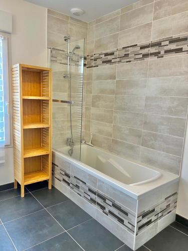 une salle de bain avec baignoire et douche en verre dans l'établissement Les Dunes, Maison proche plage, à Saint-Lunaire