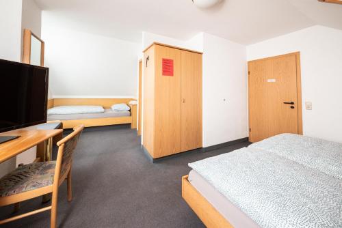 a bedroom with a bed and a desk and a television at Pension Greiser in Leipzig