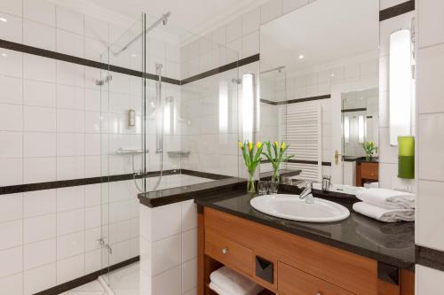a bathroom with a sink and a glass shower at Vju Hotel Rügen in Göhren