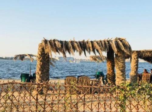 a beach with chairs and a pergola next to the water at شاليهات الهنا 3 للايجار مصيف قرية النورس الاسماعيلية in Ismailia