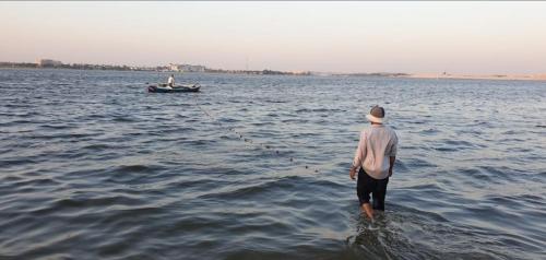 a man standing in the water with a boat at شاليهات الهنا 3 للايجار مصيف قرية النورس الاسماعيلية in Ismailia