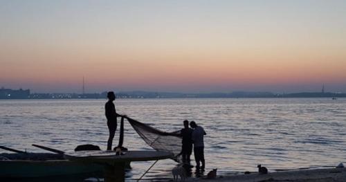 a group of people standing on the beach with a boat at شاليهات الهنا 3 للايجار مصيف قرية النورس الاسماعيلية in Ismailia