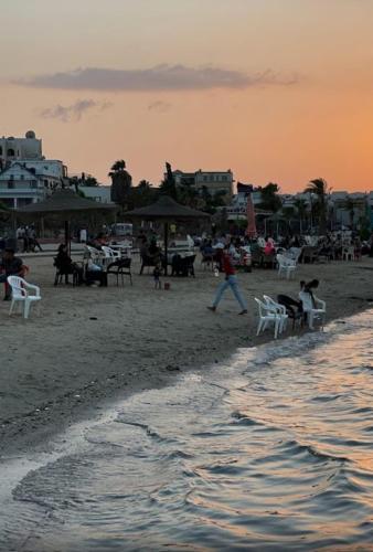 a group of people on a beach at sunset at شاليهات الهنا 3 للايجار مصيف قرية النورس الاسماعيلية in Ismailia