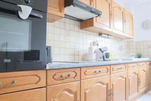 une cuisine avec des armoires en bois et un micro-ondes noir dans l'établissement Le Vintage, Mulhouse ville, à Mulhouse