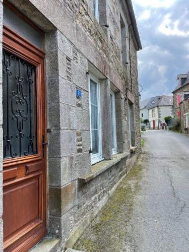 an old brick building with a wooden door on a street at Gite - Val Couesnon in Saint-Ouen-de-la-Rouërie