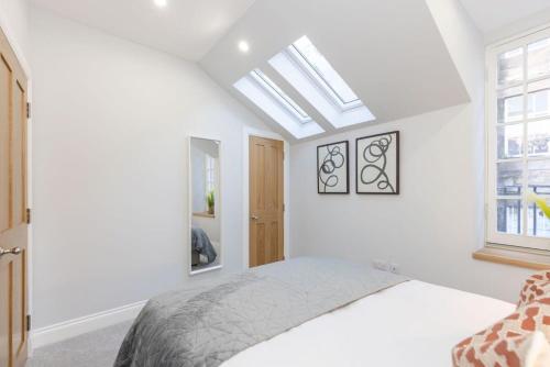a white bedroom with a bed and a skylight at Dragon Suites - Yukina Suite - 2 bed city centre house with garden in Edinburgh