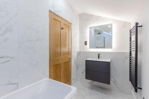 a bathroom with a sink and a wooden door at Dragon Suites - Yukina Suite - 2 bed city centre house with garden in Edinburgh