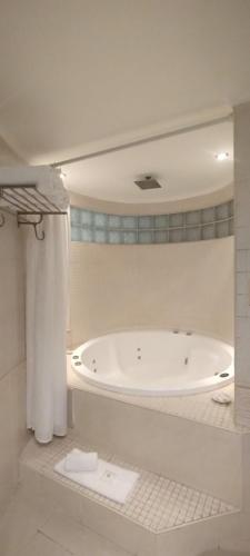 a white bathroom with a tub in a room at Plaza Real Suites Hotel in Rosario