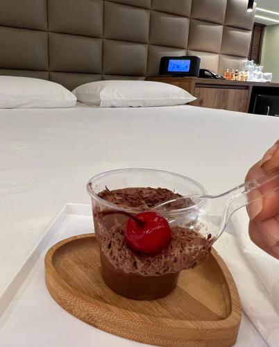 a person holding a spoon over a bowl of food at Status Motel Ourinhos in Ourinhos