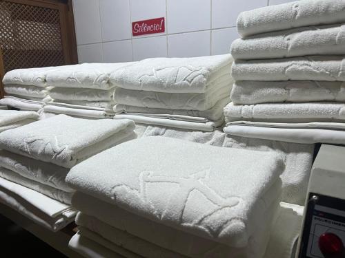 a pile of white towels on a shelf in a store at Status Motel Ourinhos in Ourinhos