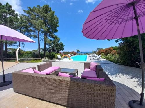 un parasol violet et quelques chaises et une piscine dans l'établissement PIANICCIA-villa standing- pieds dans l'eau-piscine privée, à Sari-Solenzara
