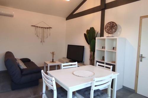 a living room with a white table and a couch at Maison climatisée proche du lac in Sanguinet