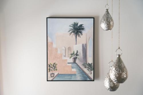 un tableau accroché au mur avec deux lumières suspendues dans l'établissement La Médina parfum d orient, à Marseille