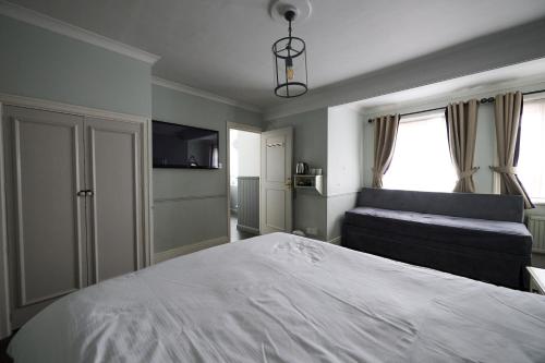 a bedroom with a large white bed and a couch at White Hart, Newmarket by Marston's Inns in Newmarket