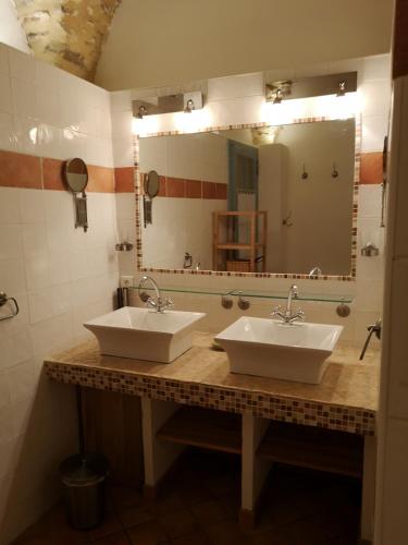 une salle de bain avec deux lavabos et un grand miroir dans l'établissement Mas de La Réboussière, à Tharaux