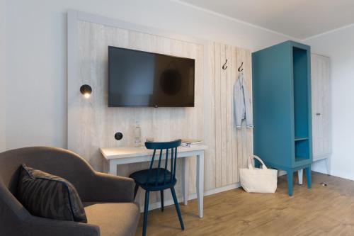 a living room with a desk and a tv on a wall at Koopmanns Hotel und Lädchen in Göhren