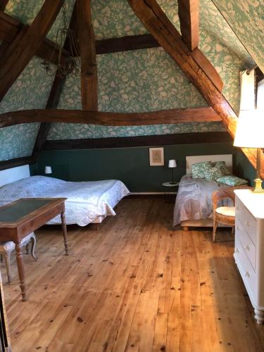 - une chambre mansardée avec 2 lits et une table dans l'établissement Maison 17 couchages en Normandie à 1h de Paris, à Molincourt