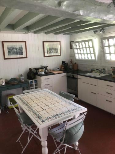 une cuisine avec une table et des chaises dans l'établissement Maison 17 couchages en Normandie à 1h de Paris, à Molincourt