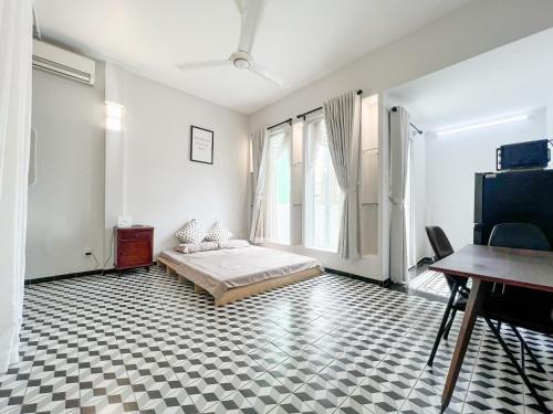 a white room with a bed and a desk and windows at Timmy's house in Ho Chi Minh City