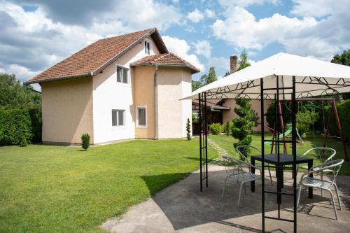 a patio with chairs and an umbrella in a yard at Guesthouse Kristina in Palić