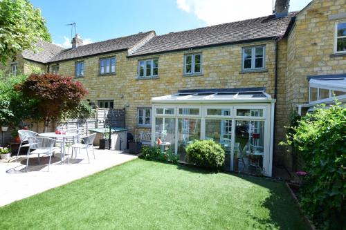 a garden in front of a house with a conservatory at Little Shrublands in Blockley