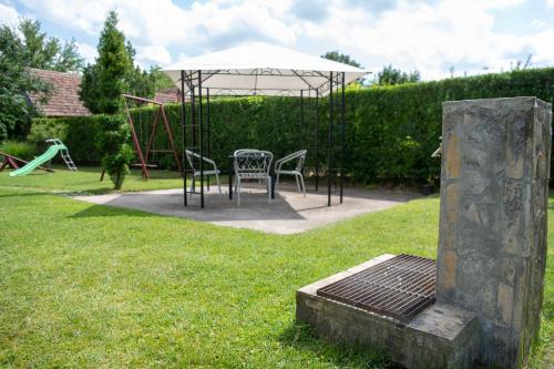 a table and chairs under an umbrella in a yard at Guesthouse Kristina in Palić