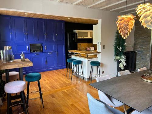 une cuisine avec des placards bleus, une table et des tabourets dans l'établissement La maison Swan, à Gérardmer