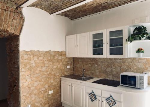 a kitchen with white cabinets and a microwave at Al Mare Fuori in Calopezzati