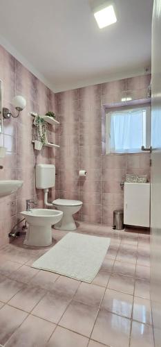 a bathroom with a toilet and two sinks and a window at LUKA APARTMENT in Posedarje