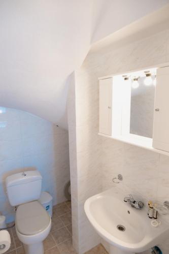 a white bathroom with a toilet and a sink at Elounda Residence Resort & Waterpark in Elounda
