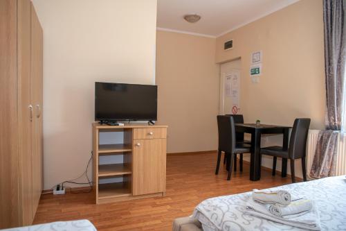 a room with a television and a table and chairs at Guesthouse Kristina in Palić