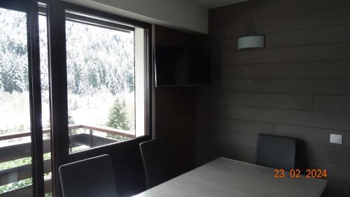 une pièce avec une table et une grande fenêtre dans l'établissement Le Tavaillon, au Grand-Bornand