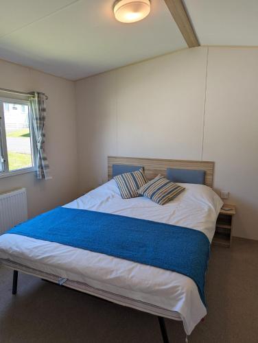 ein Schlafzimmer mit einem großen Bett mit einer blauen Decke in der Unterkunft LOVELY BRIGHT MODERN CARAVAN SWANAGE on PEACEFUL AND TRANQUIL HOLIDAY PARK in Swanage