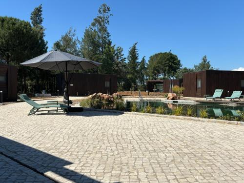 a patio with an umbrella and chairs and a pool at Refúgio da Quinta Nere Maitia in Santarém