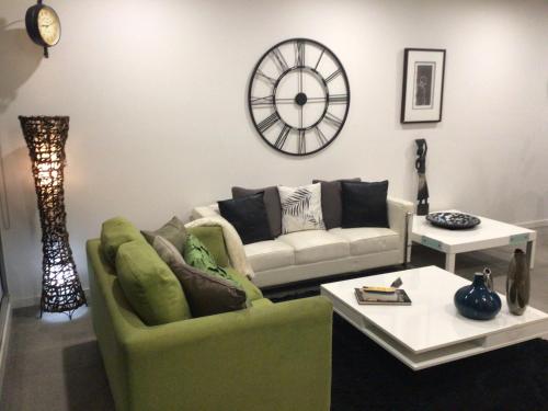 a living room with a couch and a clock on the wall at Bundoora Uni Hill 2bdr 2bth 1car in Bundoora
