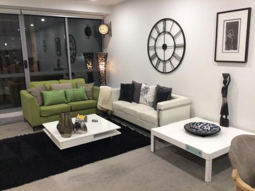 a living room with couches and a clock on the wall at Bundoora Uni Hill 2bdr 2bth 1car in Bundoora