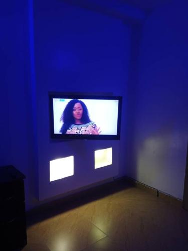a tv in a blue room with a woman on the screen at Morada Hotels Ltd in Lagos