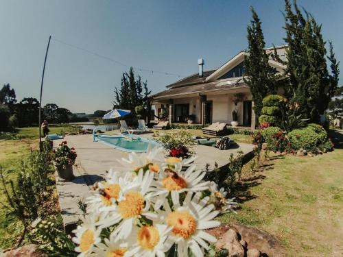 ein Haus mit weißen Blumen vor einem Hof in der Unterkunft Sítio Bela Vista 40 in Santa Maria do Erval