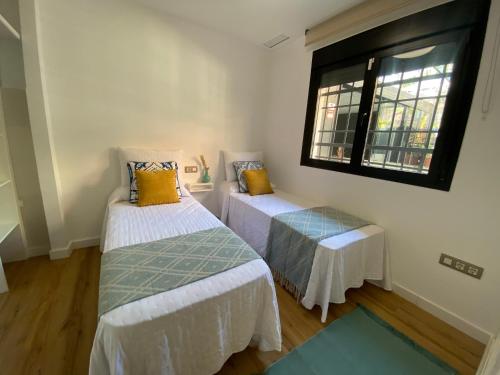 two beds in a room with a window at El Paraíso de Fuentebravía - Primera Línea de Playa in El Puerto de Santa María