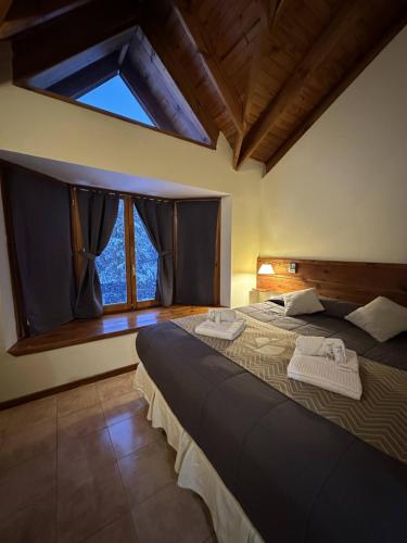 une chambre avec deux lits et une grande fenêtre dans l'établissement Posada del Ciprés, à Villa La Angostura