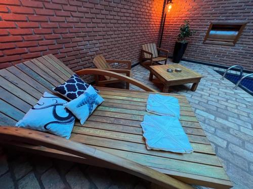 a wooden bench with two pillows and a table at Status Motel Ourinhos in Ourinhos